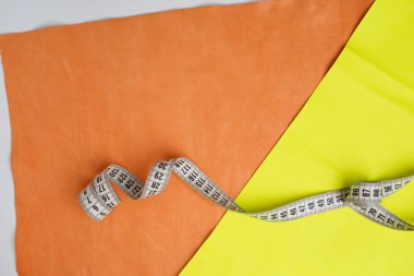 Turuncu ve sarı deri parçaları ve bükülmüş bir santimetre..