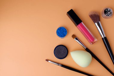 Üç makyaj fırçası, allık için fırça, göz farı, ruj, temel sünger, göz farı ve pembe ruj. Randevuya hazır ol. Uzayı kopyala Şeftali arkaplan.