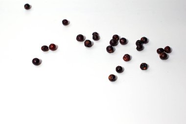 Kurutulmuş ardıç meyveleri beyaz arka plana saçılmış. Baharat. İzole et.