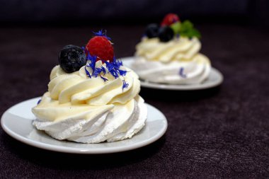 Madam Pavlova 'ya taze ahududu ve böğürtlenli nane ve mısır çiçeğiyle süslenmiş tatlı verin. Kremalı ve kremalı hafif tatlı..