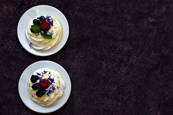 デザートマダム パブロワには ミントとコーンフラワーで装飾された新鮮なラズベリーとブルーベリーがあります メレンゲとクリームの軽いデザート コピースペース — ストック写真