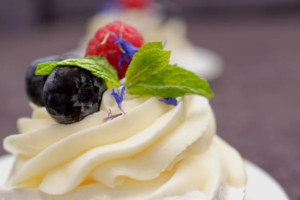 デザートマダム パブロワには ミントとコーンフラワーで装飾された新鮮なラズベリーとブルーベリーがあります メレンゲとクリームの軽いデザート — ストック写真