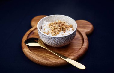 Mısır gevreği serpilmiş yulaf lapası, ahşap bir büfede kaşıkla duruyor.