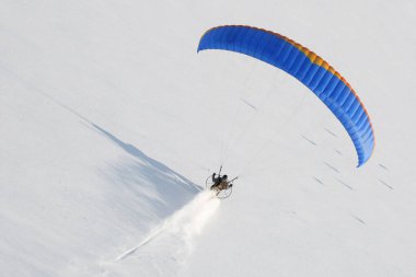 Paramotor kışın gökyüzünden görünen alçak irtifada uçan ve bakir karda iz bırakan