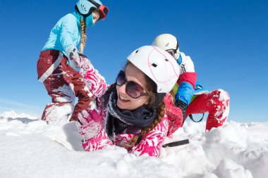 Renkli elbiseli genç kızları kapatın kayak pistlerinde taze karda oynayın ve dağlarda mavi gökyüzü