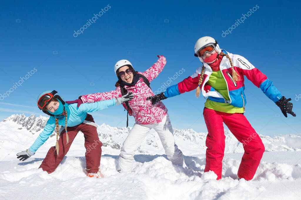 Three girls on winter vacation in the Alps posing in the snow on the ski slopes. Fun activity in the snow