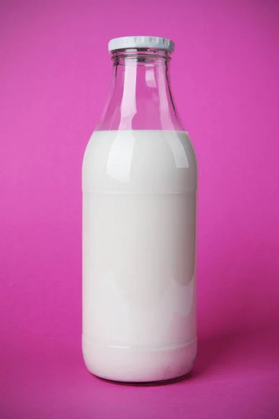 早餐吃得好 玻璃瓶里装满了鲜牛奶 钙对你的健康有好处 带有阴影的粉色背景照片 — 图库照片
