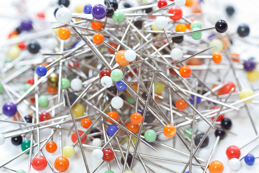 Multicolored sewing pins or push pin needles laid loose on white background