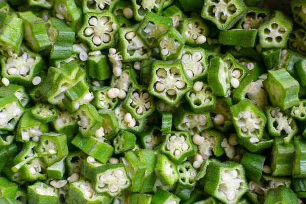 新鮮に刻んだ野菜の背景オクラは女性の指としても知られています この野菜の学名はAbelmosus Esculentusです オクラは 有益な栄養素や抗酸化物質が豊富な食用の種子鞘で知られる開花植物です — ストック写真