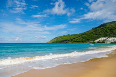 Sahildeki güzel deniz manzarası. Plajın her tarafına yayılan açık mavi dalgalar Altın Kum 'u pürüzsüz bir şekilde yumuşatıyor. Uzakta, kıyı şeridi yakınında bir otel görülebilir..