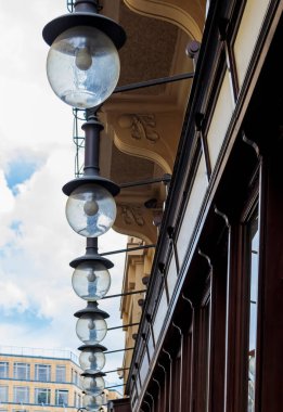 Yuvarlak fenerler, elektrik lambasının içinde, metal tepeler binanın ön cephesinde, çatı örtüsünün altında asılı..