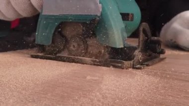 Tahta paneli elektrikli aletle kesen adam.