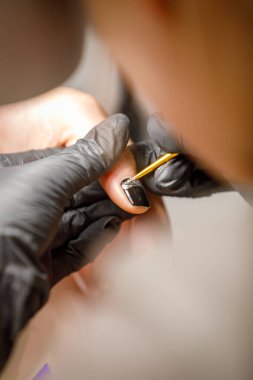 Güzellik stüdyosunda, usta manikür yapar, fırçayla çiviye bir desen uygular..