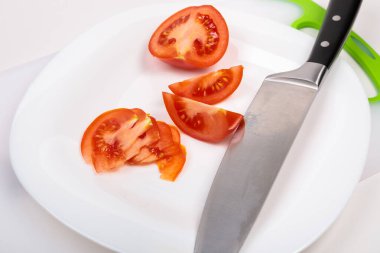 Kesme tahtasının üzerinde taze kırmızı bir domates ve büyük bir şef bıçağı var. İzole edilmiş beyaz bir arkaplanda.