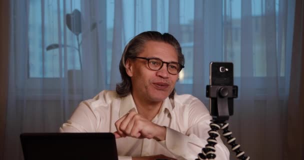 บล็อกเกอร์อายุ 50 ปีที่มีแว่นบันทึกวิดีโอจากที่บ้านบนสมาร์ทโฟนของเขา . — วีดีโอสต็อก