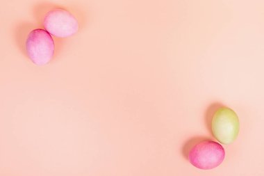 Paskalya. Üniformalı pembe arka planda çok renkli yumurtalar ve mesaj için yer var. Yukarıdan görüntüle