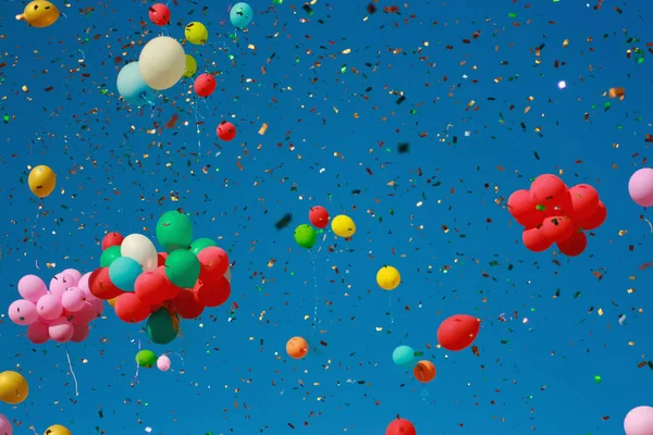 Multicolored glitter balloons launched into the blue sky.