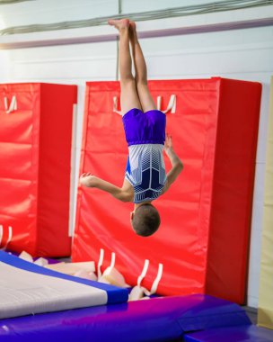 A young guy performs a jump somersault, in training.