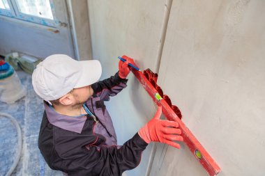 Bir adam, bir elektrikçi bir kalem ve mezura ile soketler için delikler açar.