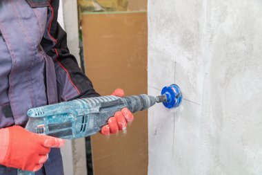 Bir elektrikçi elmas çekirdekli soketler için delik açıyor.
