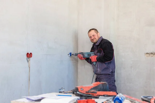 Bir elektrikçi elmas çekirdekli soketler için delik açıyor.