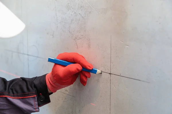 Чоловік, електрик виділяє отвори для розетки олівцем, міра стрічки Стокова Картинка