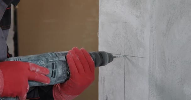 전기 기술자가 전동 공구를 사용하여 벽에 구멍들을 뚫는다. — 비디오