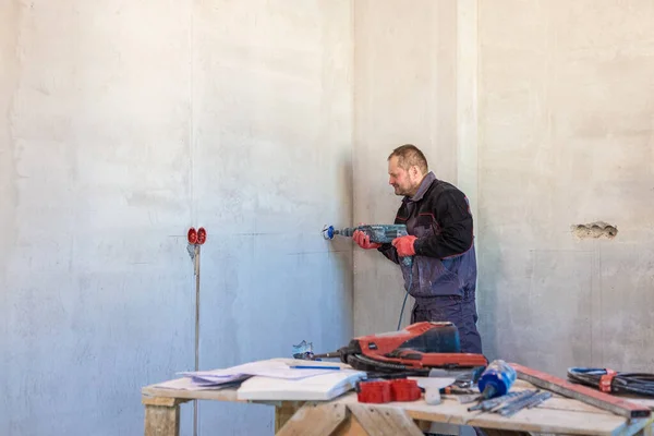 An electrician drills holes for sockets with a diamond core bit