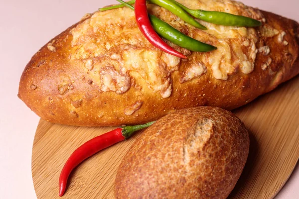Kırmızı ve yeşil biberli kesme tahtasındaki taze ekmek..