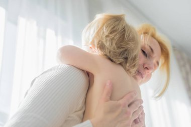 Annem sevecen bir şekilde pencerenin önünde bebeğe sarılıyor..