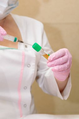 Uzman, şırınga kullanarak test tüpünden kan plazmasını alıyor..