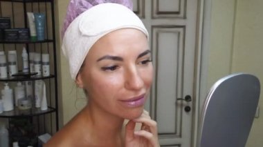 Genç bir kız masajdan sonra aynada yüzüne bakar..