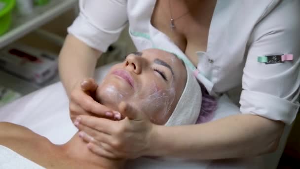 Dans le salon de beauté, la jeune fille reçoit un massage du visage et du cou à la crème. — Video