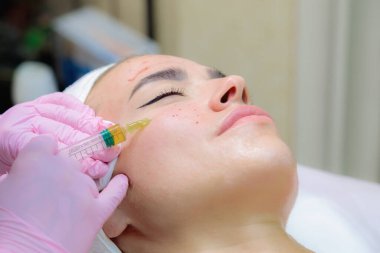 Doktor genç bir kızın yüzüne kan plazması enjekte ediyor..