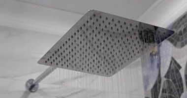 Banyodaki büyük kare bir duş başlığından su akar.