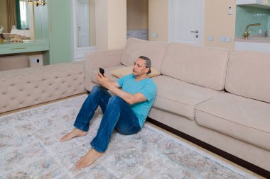 Yetişkin bir adam sosyal ağları cep telefonuyla tarar.