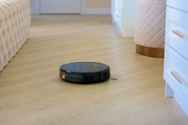 Dairesel robot süpürge oturma odasındaki döküntüleri topluyor..