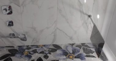 Banyodaki büyük kare bir duş başlığından su akar.