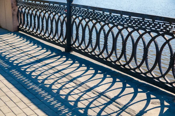 Schatten an einem sonnigen Tag vom Metallgeländer an der Brücke über den Fluss — Stockfoto