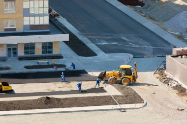 Özel ekipman işçileri inşaat halindeki bir evin yanında asfalt döşüyorlar..