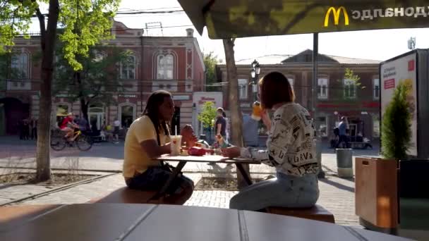 Czelabińsk, Rosja, 17 maja 2021 r. Biała dziewczyna i czarny mężczyzna jedzą lunch na otwartej przestrzeni postu — Wideo stockowe