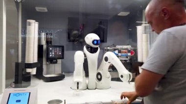 Chelyabinsk, Rusya, 17 Mayıs 2021. Havaalanı büfesinde bir robot müşteriye hizmet eder. Dondurma koyuyor.
