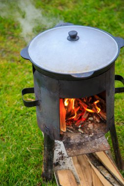 Cooking in a cauldron on the fire. Picnic outdoors in summer.