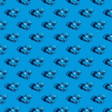 Seamless pattern of glasses with water on a blue background.