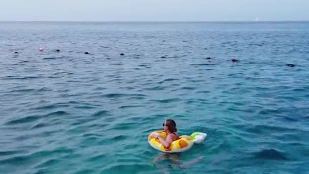 年轻漂亮的姑娘坐在橡皮圈上在海里游泳 一个长头发 黄圈的女孩 后续行动 — 图库视频影像