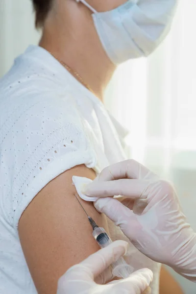 A girl doctor in white gloves makes a vaccination, a vaccine against coronavirus, flu. — Stock Photo, Image