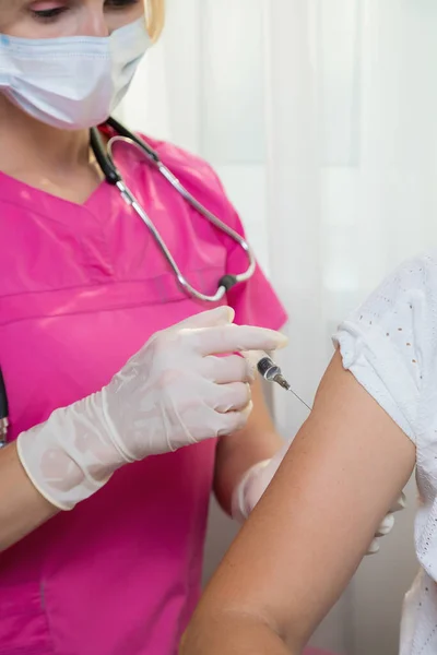 A girl doctor in white gloves makes a vaccination, a vaccine against coronavirus, flu. — Stock Photo, Image