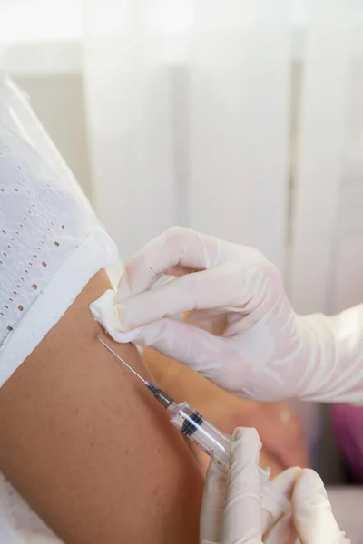Una ragazza medico in guanti bianchi fa una vaccinazione, un vaccino contro il coronavirus, influenza. — Foto Stock