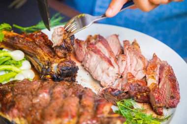 Bir adam pişmiş eti tabakta keser. Akşam yemeği için fırında et..