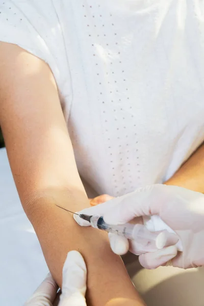 A girl doctor injects a syringe on her arm into a vein of an adult woman. — Stock Photo, Image